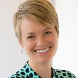 A woman with short blonde hair smiles for the camera.