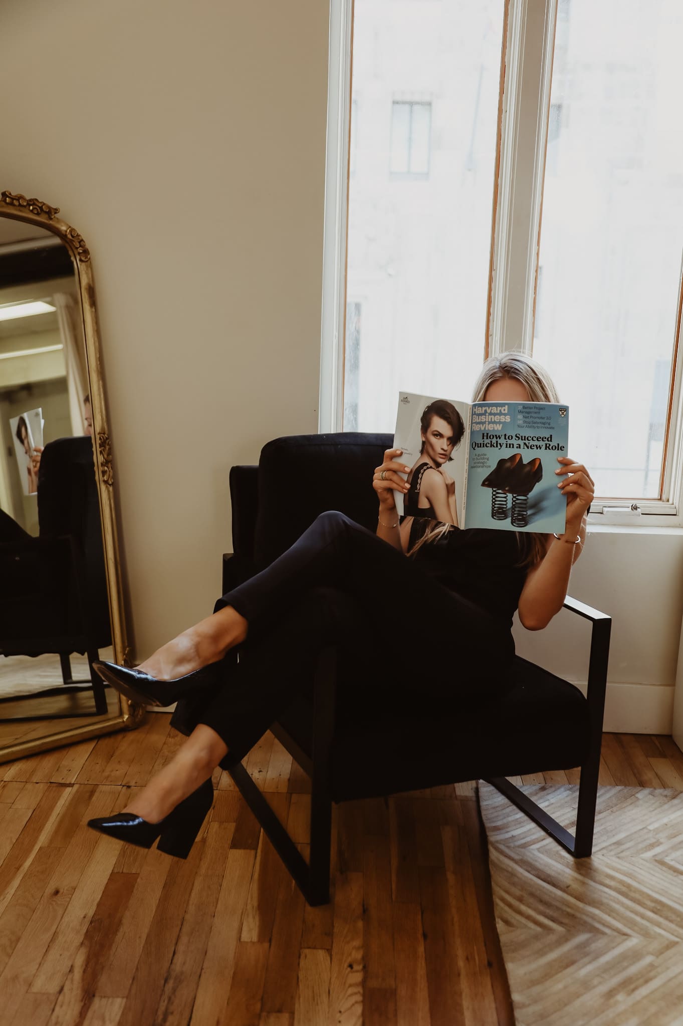 A woman sitting in a chair reading a magazine.