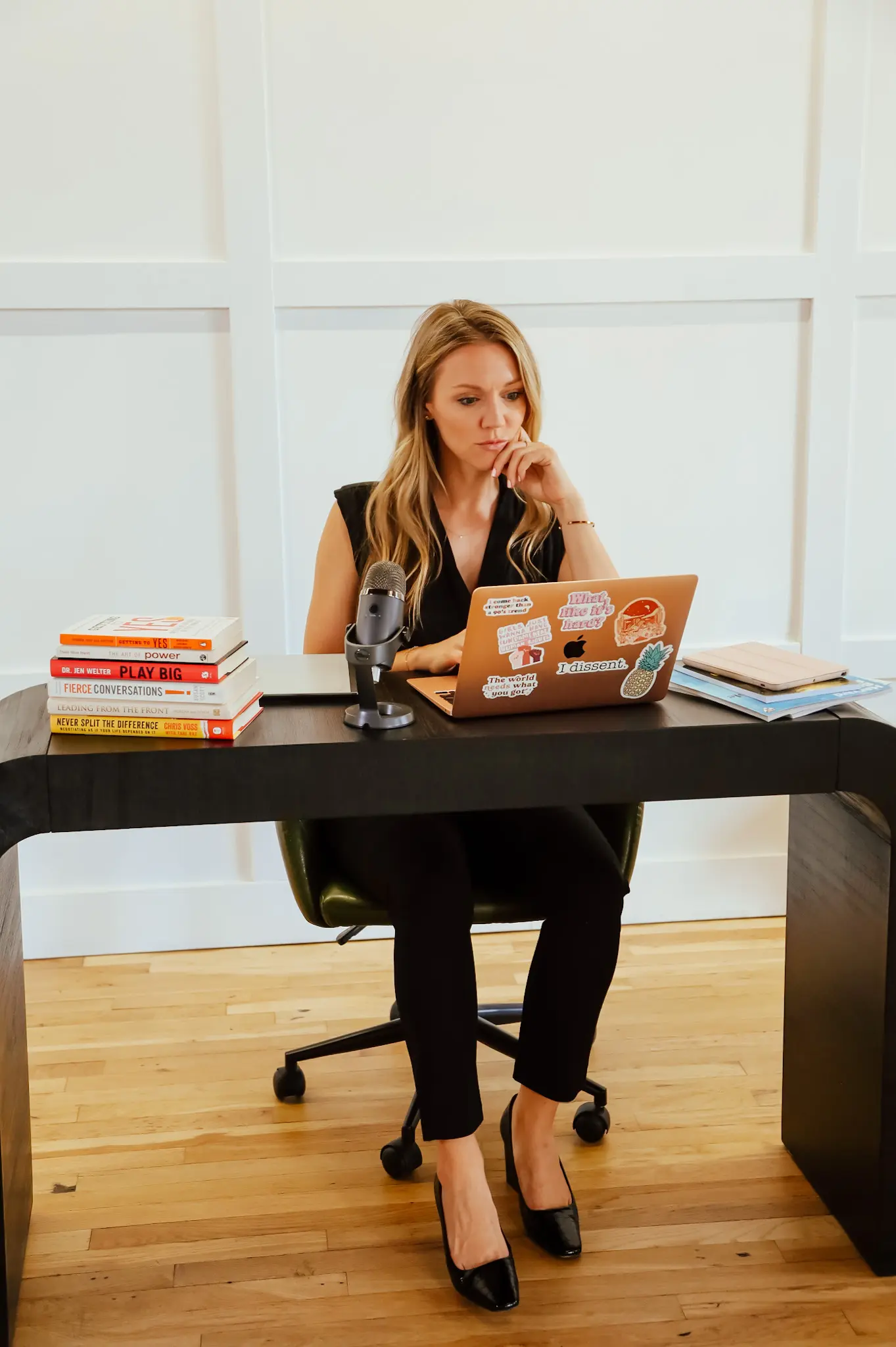 A woman sitting at her desk with books and a laptop.