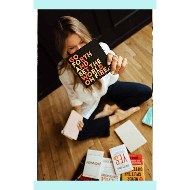 A woman sitting on the floor holding onto some books