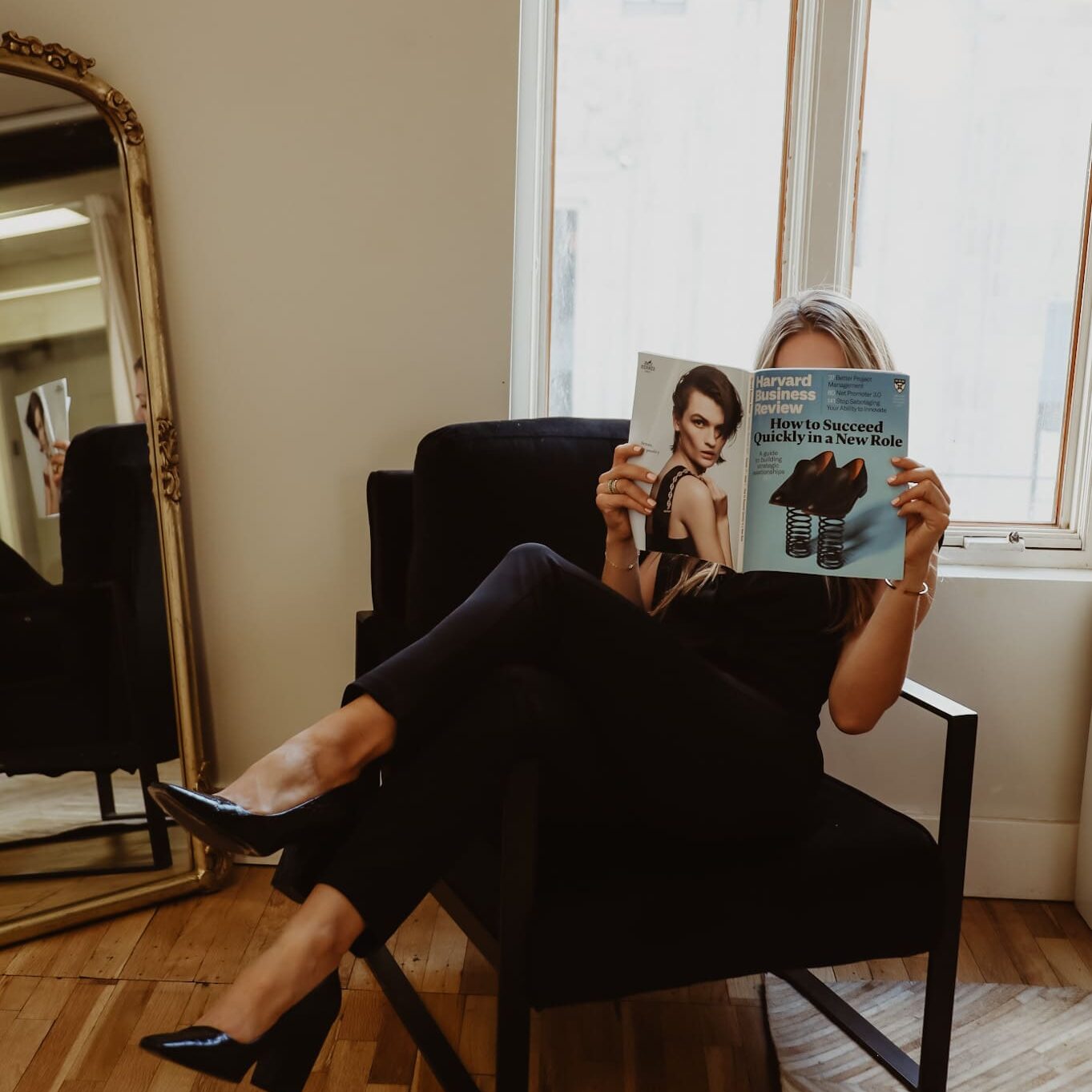 A woman sitting in a chair reading a magazine.